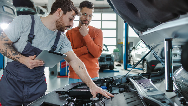 mechanic and customer looking at EV motor
