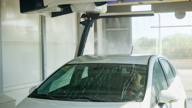 car being cleaned in a laser car wash with a women in the driving seat
