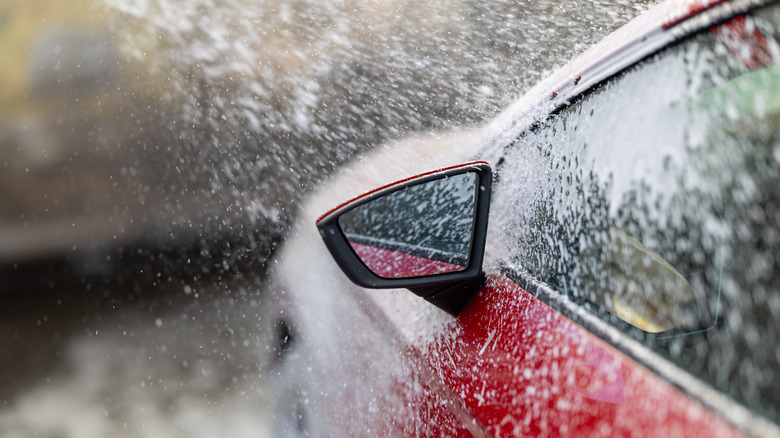 red car being sprayed with foam in an automatic car wash