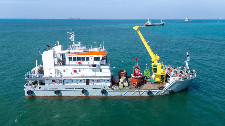 A boat working on a red buoy in the ocean.