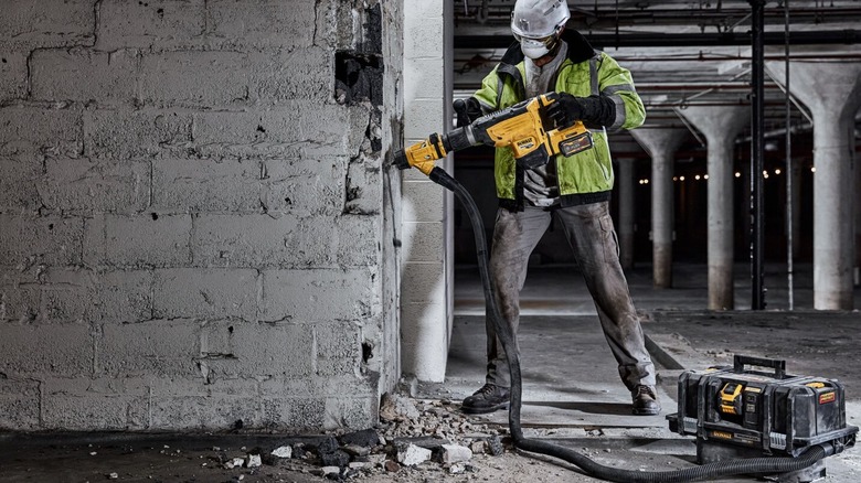 A worker using a DeWalt concrete hammer and dust extractor
