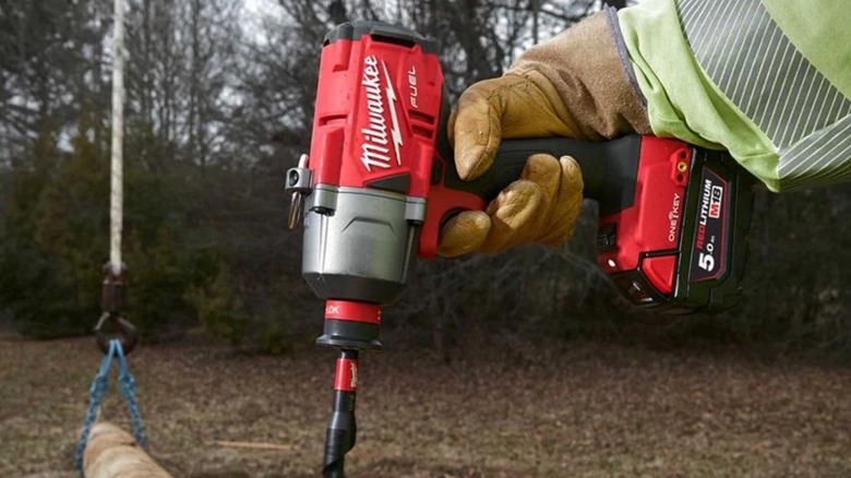 A person using a Milwaukee impact wrench outside.