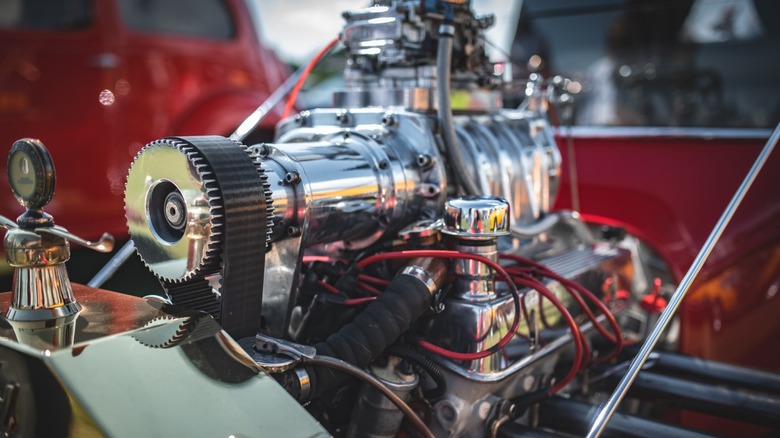 A close-up of a large chromed supercharger atop a vintage car engine.