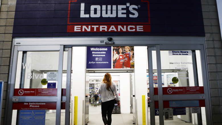 A woman walking into a Lowe's store via the main entrance.