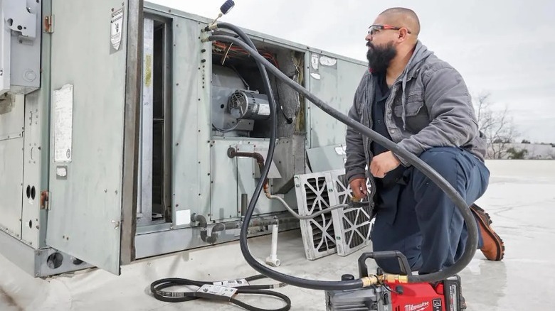 Technician using a M18 5 CFM Fuel Vacuum Pump on HVAC unit