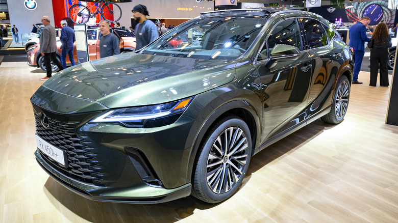 A green Lexus RX 450h+ on display at an auto show