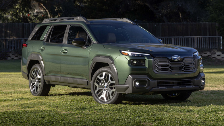 The standard variant of the 2026 Subaru Outback parked in a lawn, front 3/4 view, green exterior.