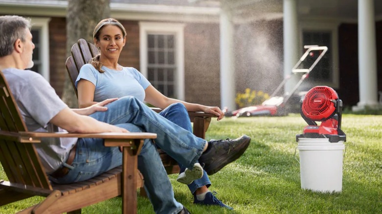 man and woman sitting in front of misting fan