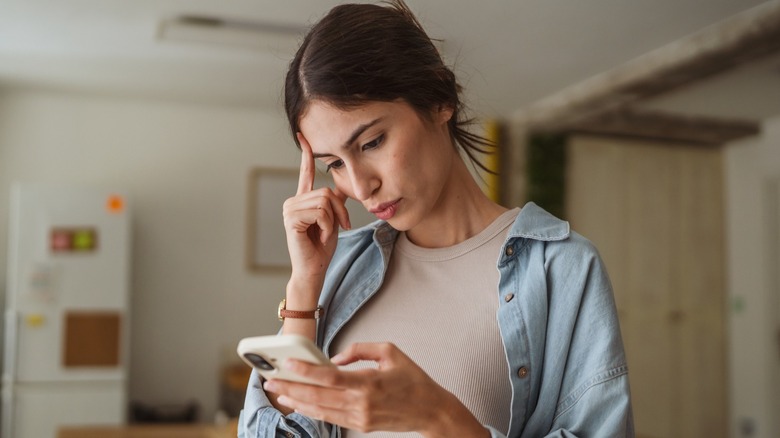 Woman staring at her phone and contemplating