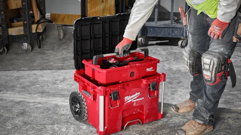 a person removing an interior organizer tray from a milwaukee packout base box