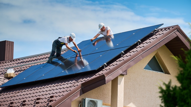 Workers installing solar panels on the roof of a home