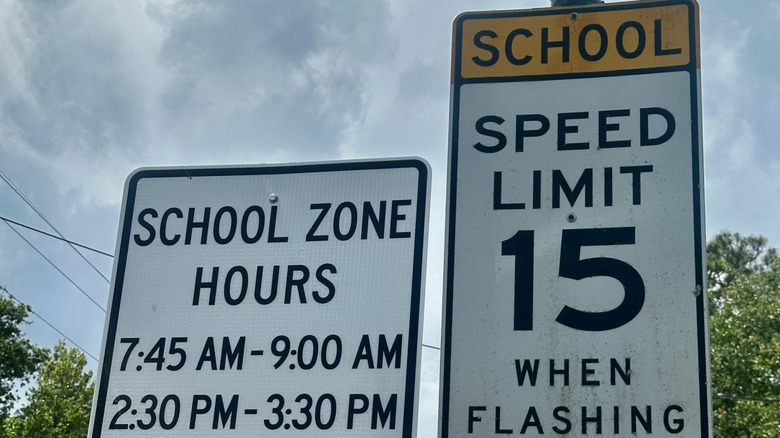 A school speed limit sign alongside a sign posting school zone hours
