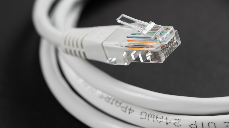 A big closeup of a white/gray Ethernet cable on a black desk