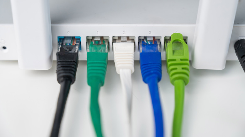 Five Ethernet cables of different colors (black, green, white, blue, and bright green) plugged in a router