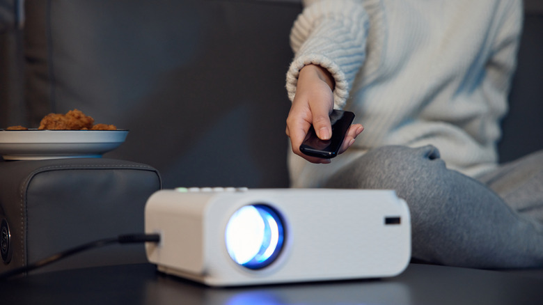 A person using a remote control to change settings on a home theater projector