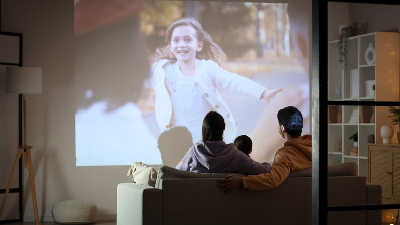 A family watching entertainment on a projector with the picture looking a bit washed out