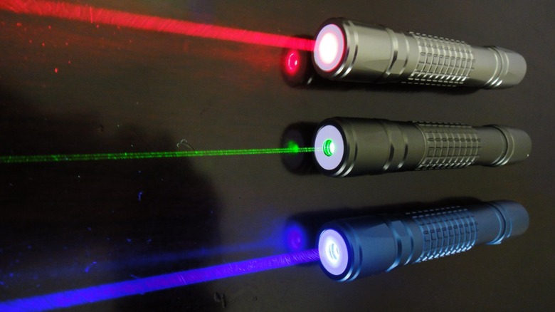 Three laser pointers emitting red, green, and blue beams