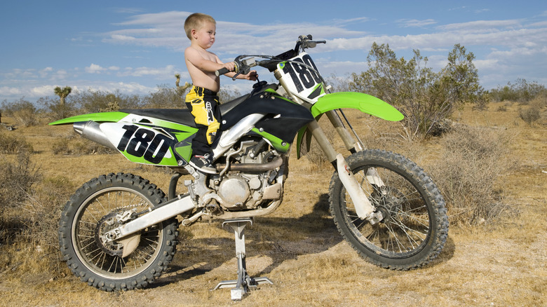 small child standing on dirt bike