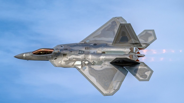 An F-22 Raptor flying with its afterburners lit