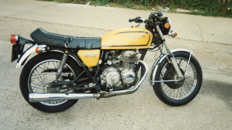 A yellow Honda CB400F parked on a driveway, side view