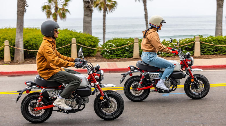 A man and a woman riding on red 2025 Honda Monkey mini-bikes