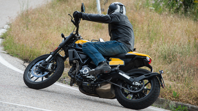 A rider taking a corner on a Ducati Scrambler 800, rear 3/4 view