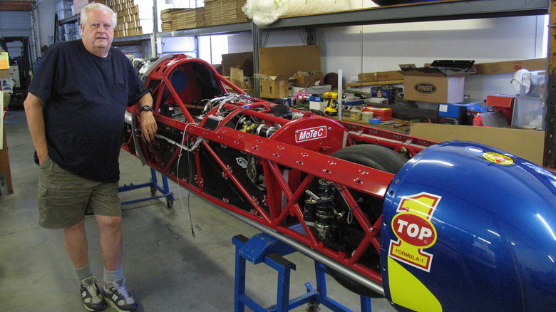 Mike Akatiff standing next to uncovered chassis of the Top 1 Ack Attack motorcycle
