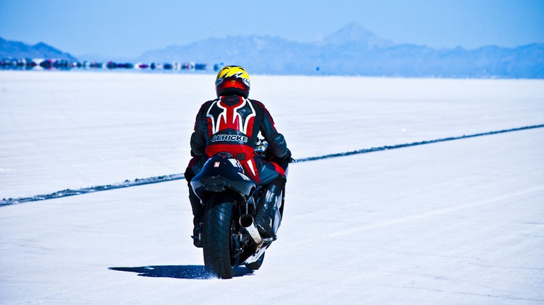 Motorcyclist riding on salt flats with blue mountains on horizon