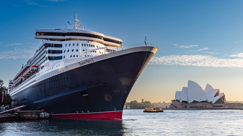 The Queen Mary 2 docked with the Sydney, Australia opera house in the background.