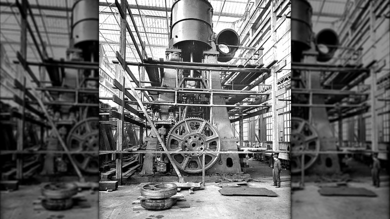 A man standing next to one of the two triple-expansion reciprocating engines for the RMS Titanic.
