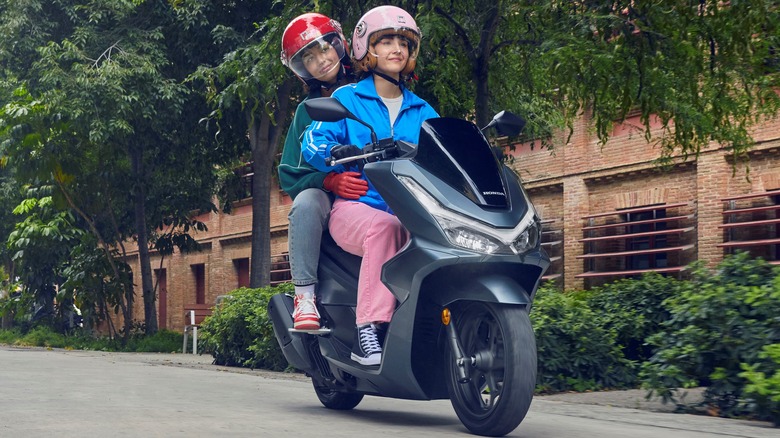 Rider and passenger on a 25YM Honda PCX125 Scooter cruising