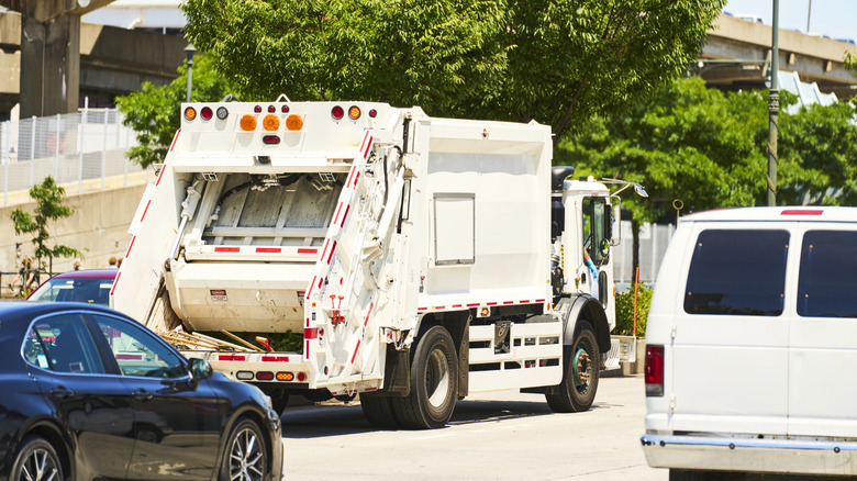 Rear view of garbage truck on a busy road.