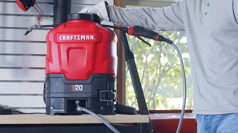 Man picking up Craftsman 20V backpack sprayer from table