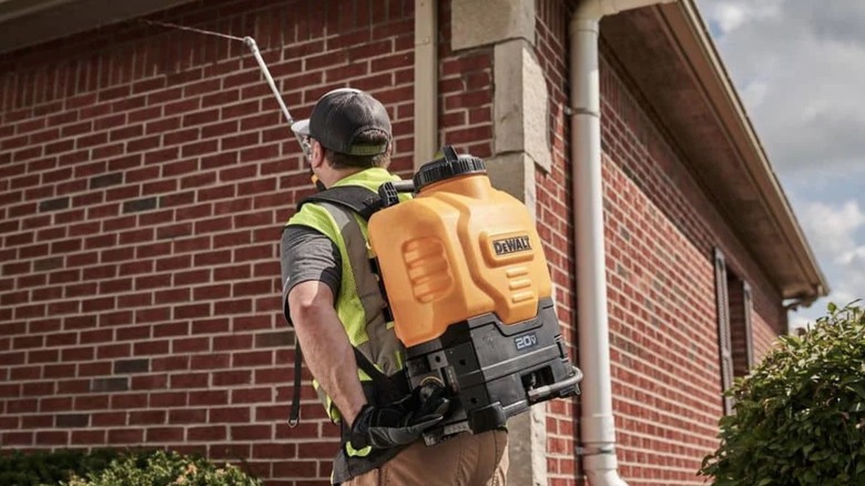 Man using DeWalt backpack sprayer on a wall