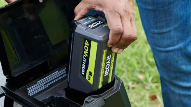 A person putting a Ryobi battery into a Ryobi tool.