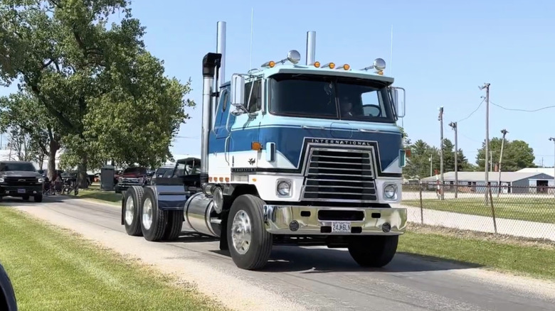 Blue and silver International Harvester Cabover Transtar 4070B Truck on a narrow road.