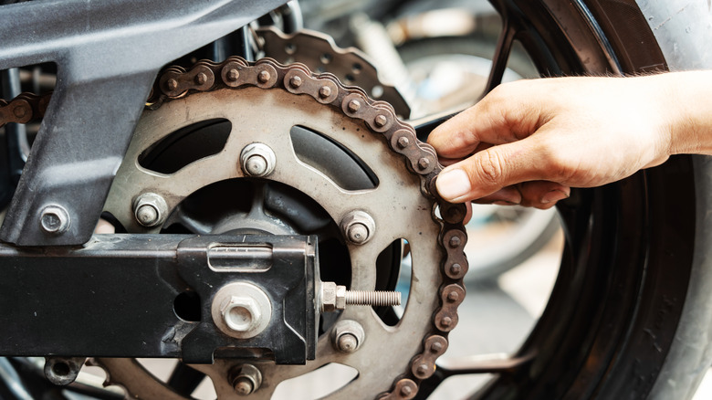 Hand grabs rusted chain on motorcycle