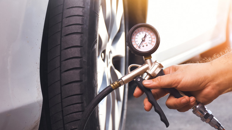 hand holding tire inflator next to wheel