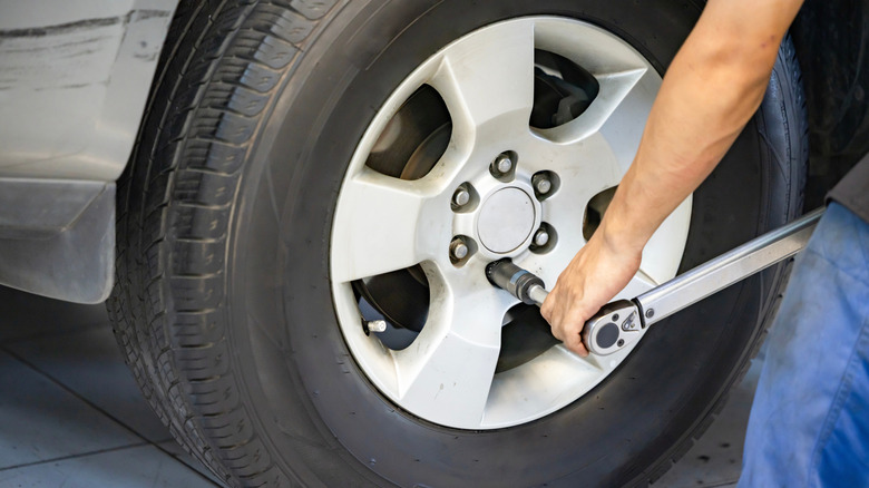 Auto mechanic using Torque wrench to inspect the wheel nuts