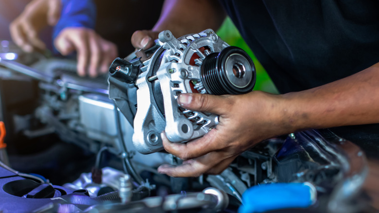 Mechanics replacing the alternator
