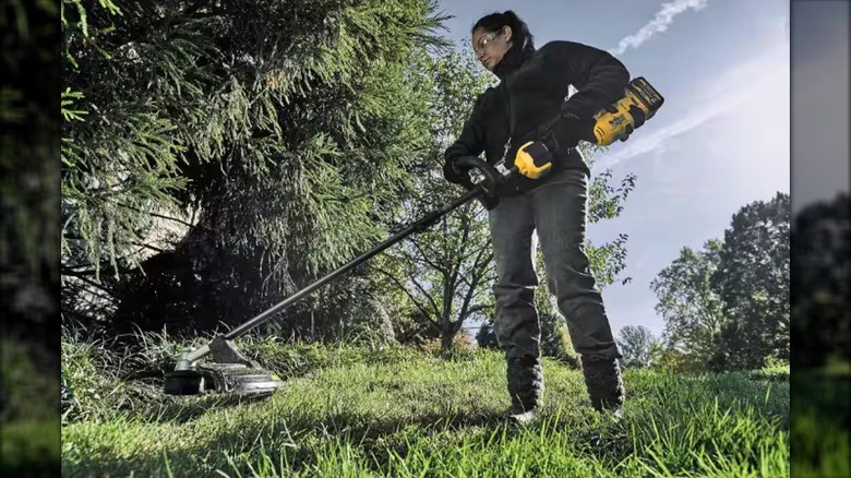 A Woman Using A DeWalt FLEXVOLT 60V 17-Inch String Trimmer On Large Lawn