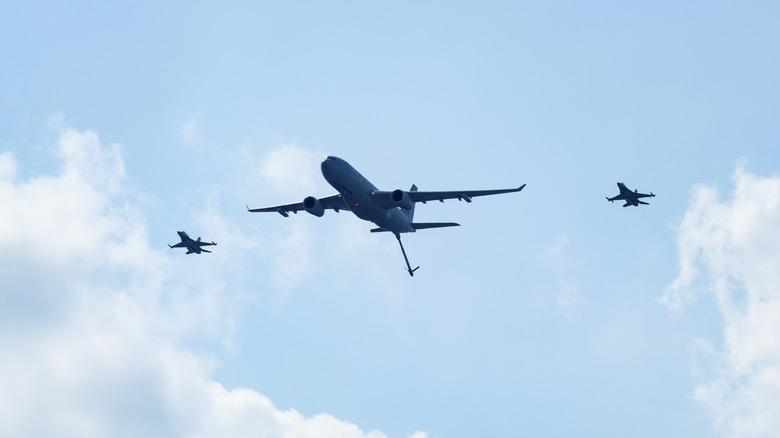 Military aircraft tanker with two fighter jets