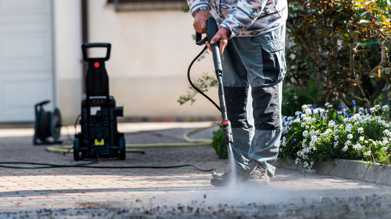 Person spraying ground with pressure washer