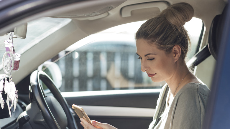 Woman in car looking at phone