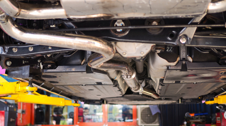 An image of the underside of a car placed on a vehicle lift.