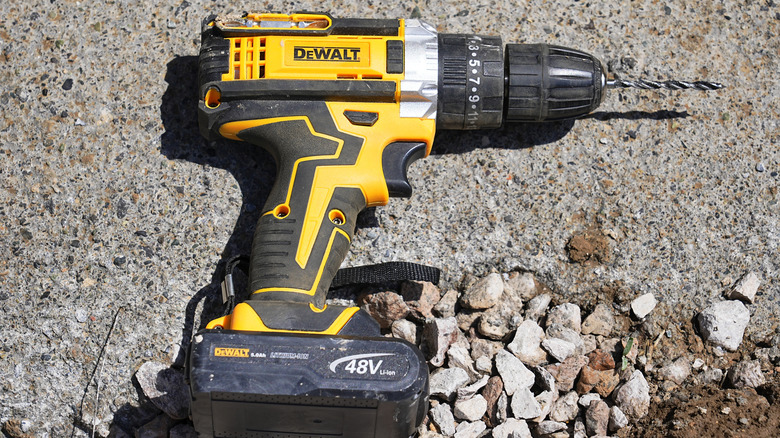 A DeWalt drill on the ground.