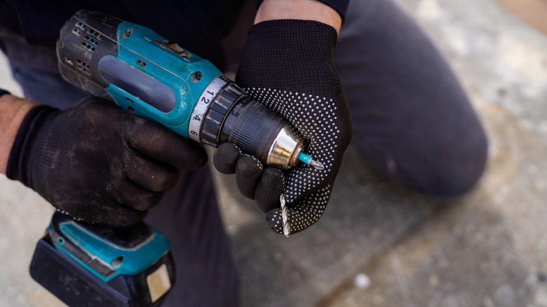 Person replaces the drill bit in a drill.