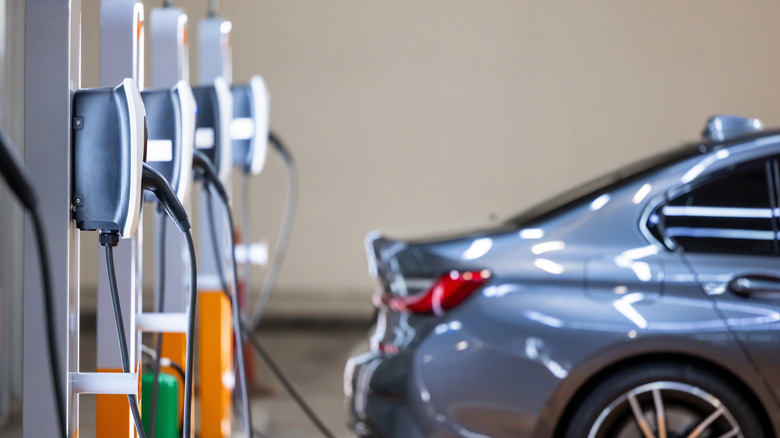 An out of focus G20 BMW 3 Series charging at an EV charging station, with other chargers in the foreground