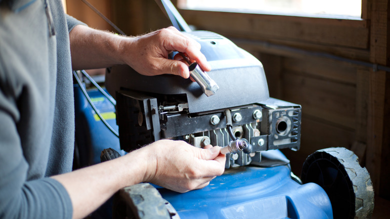 A man inspecting spark plug of his lawn mower