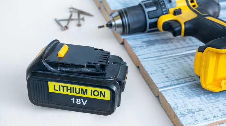Drill on top of wood besides unconnected Lithium-ion battery
